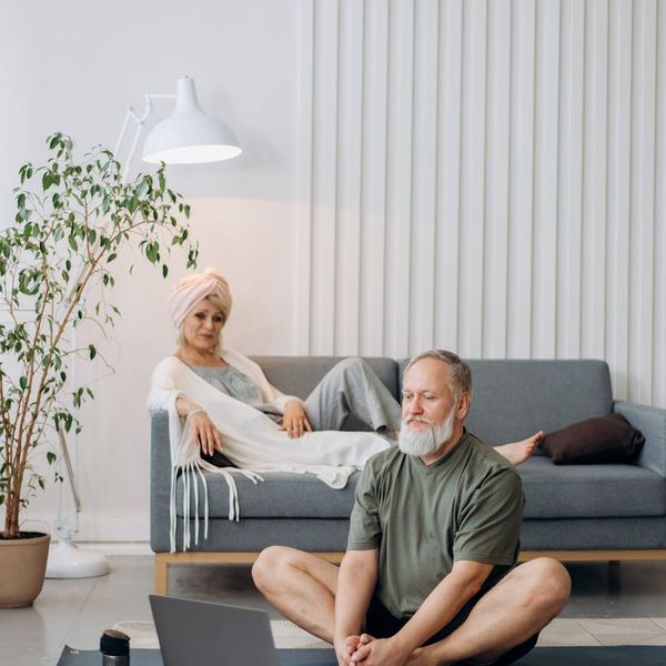 Smiling senior man stretching gently in a bright living room.